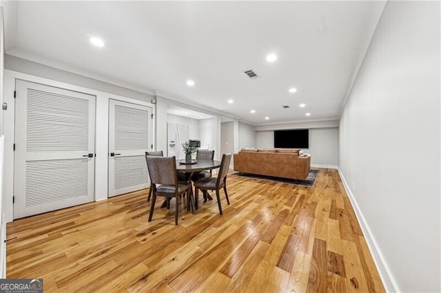 dining area with crown molding and light hardwood / wood-style flooring