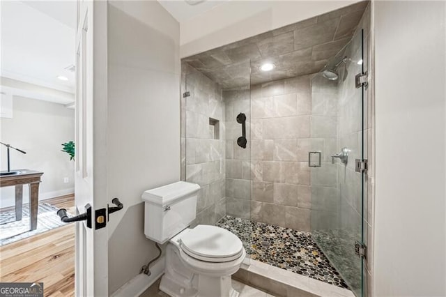 bathroom with wood-type flooring, an enclosed shower, and toilet