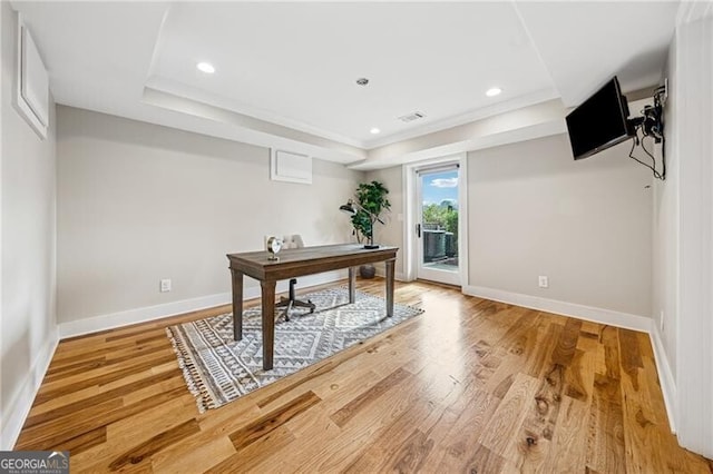 home office featuring wood-type flooring and a tray ceiling