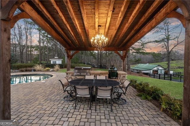 patio terrace at dusk featuring an outbuilding and grilling area