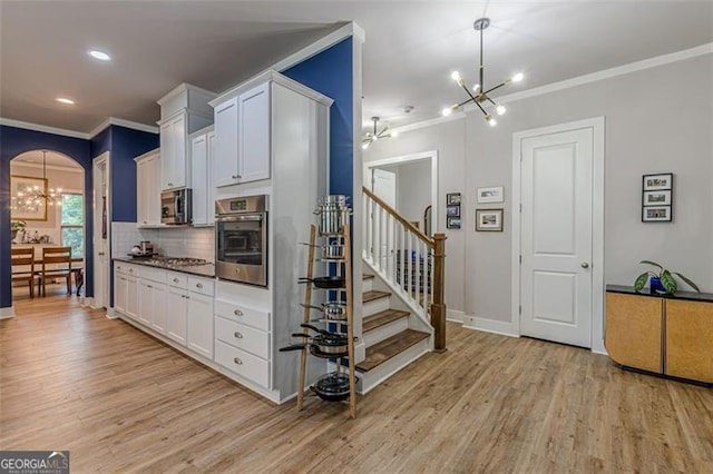 3157 Oakdale Rd, Hapeville, GA 30354 - kitchen with stainless steel appliances, a chandelier, crown molding, light wood-type flooring, and arched walkways