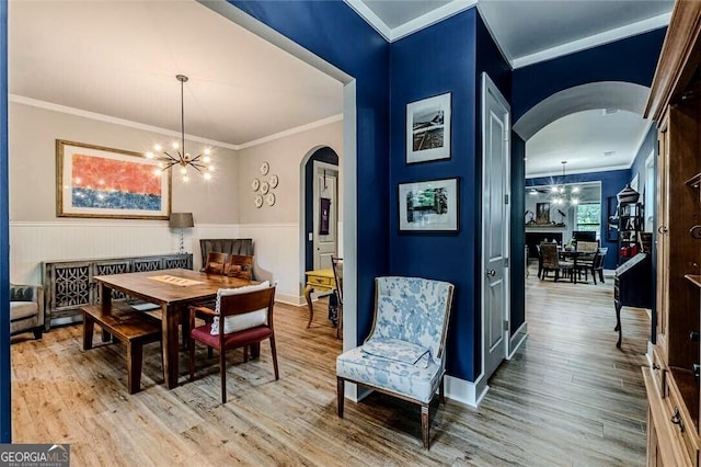 3157 Oakdale Rd, Hapeville, GA 30354 - dining room featuring arched walkways, a chandelier, crown molding, wood finished floors, and a wainscoted wall