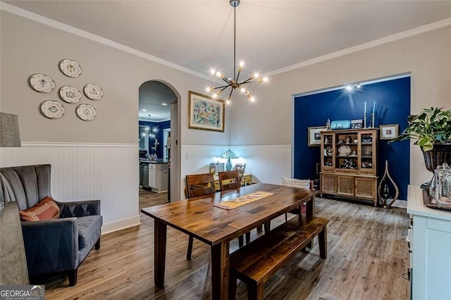3157 Oakdale Rd, Hapeville, GA 30354 - dining area featuring arched walkways, a wainscoted wall, wood finished floors, a chandelier, and ornamental molding