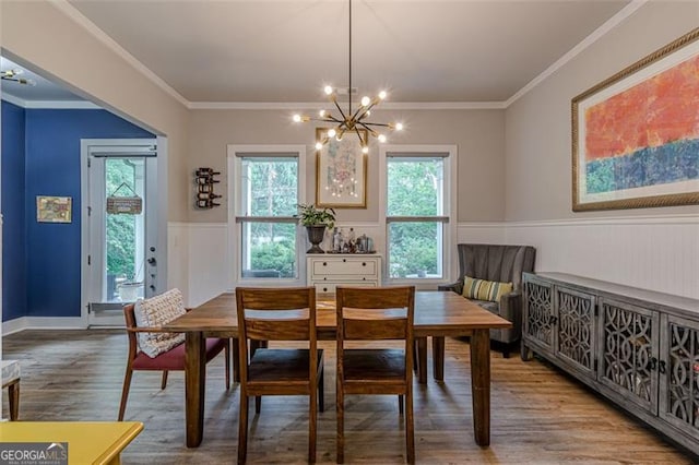 dining space with crown molding, a notable chandelier, wainscoting, and wood finished floors