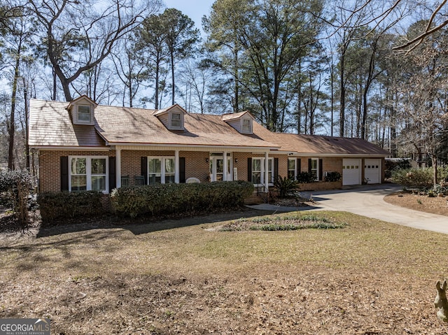 cape cod home featuring a garage and a front yard