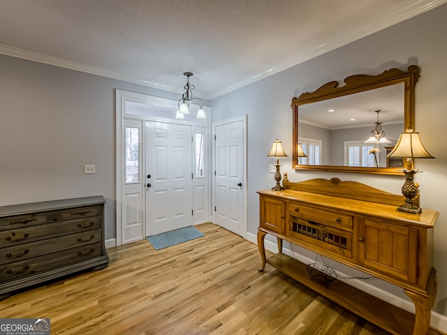 entryway featuring crown molding, a chandelier, and light hardwood / wood-style flooring