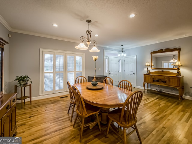 dining room featuring light hardwood / wood-style flooring, crown molding, and a textured ceiling