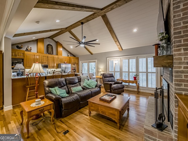 living room with beam ceiling, ceiling fan, high vaulted ceiling, light wood-type flooring, and a brick fireplace