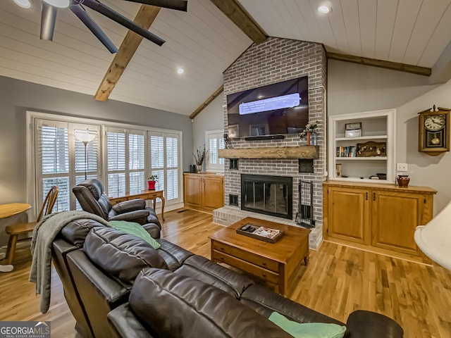 living room with light hardwood / wood-style flooring, vaulted ceiling with beams, ceiling fan, wood ceiling, and a fireplace