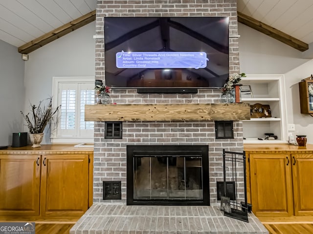 details with beamed ceiling, wood ceiling, and a brick fireplace