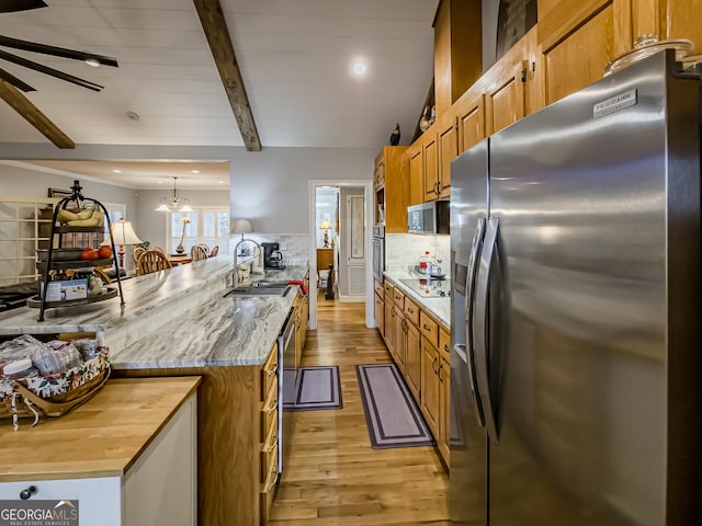 kitchen featuring sink, pendant lighting, beamed ceiling, stainless steel appliances, and decorative backsplash