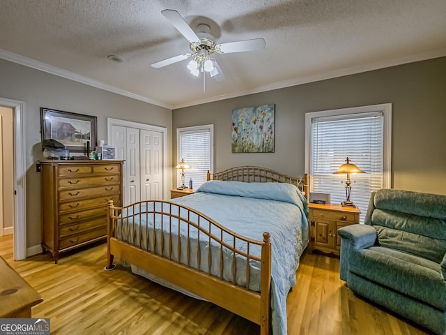 bedroom featuring a closet, a textured ceiling, light hardwood / wood-style floors, crown molding, and ceiling fan