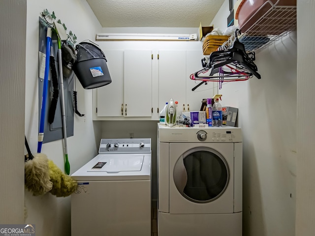 clothes washing area with washing machine and dryer, cabinets, and a textured ceiling