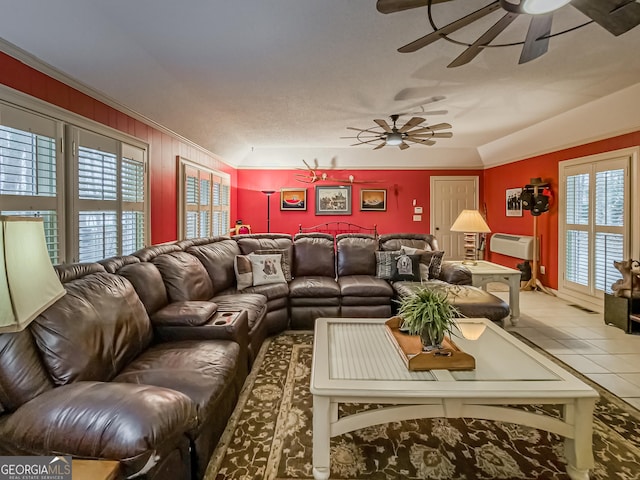 tiled living room with ceiling fan and crown molding