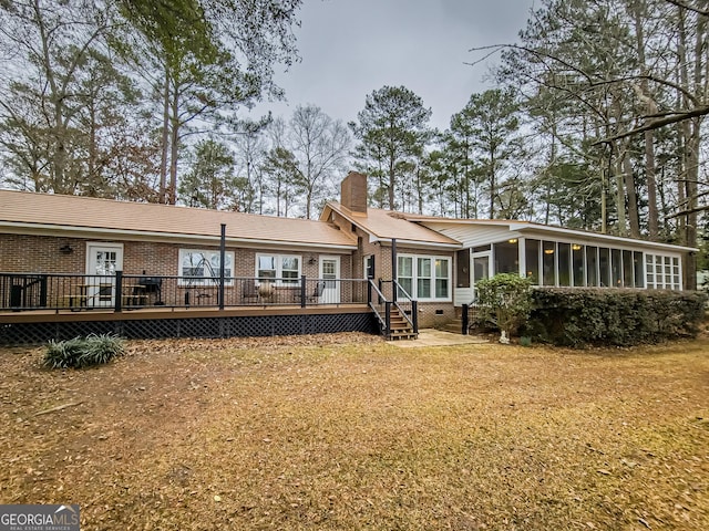 back of house featuring a lawn, a sunroom, and a wooden deck