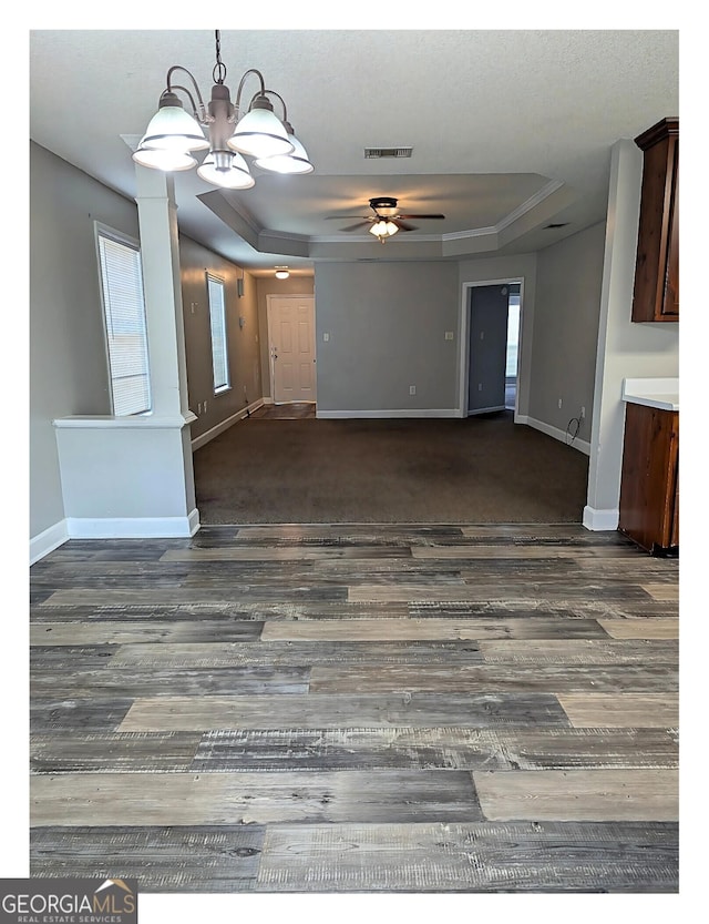 unfurnished living room with a tray ceiling, dark hardwood / wood-style flooring, and ceiling fan with notable chandelier