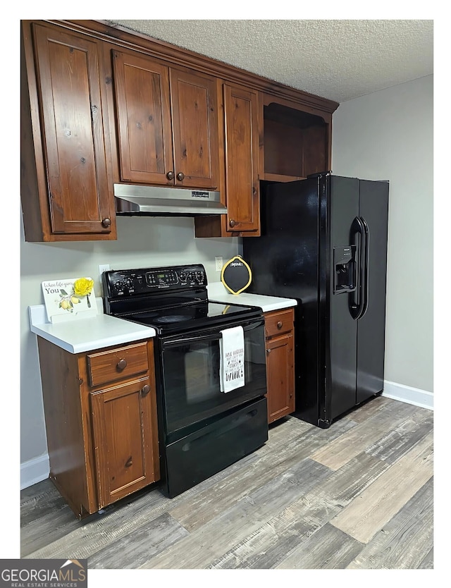 kitchen featuring a textured ceiling, light hardwood / wood-style flooring, and black appliances