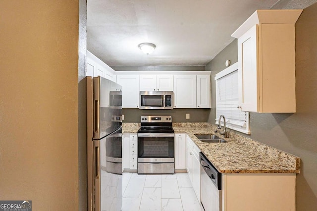 kitchen featuring stainless steel appliances, light stone countertops, sink, and white cabinets