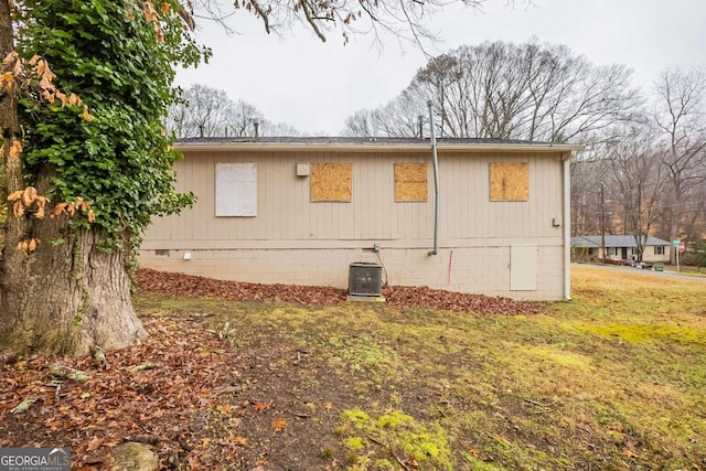 view of side of property featuring a yard and central AC