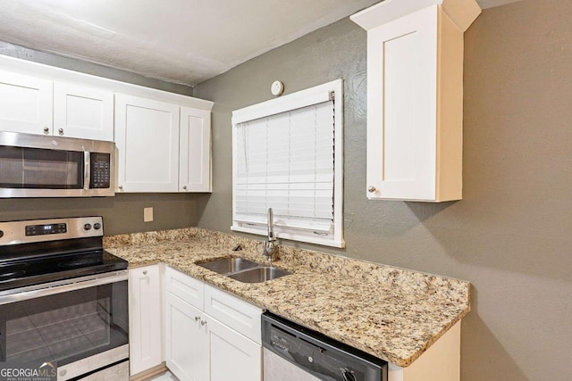 kitchen featuring white cabinetry, appliances with stainless steel finishes, light stone countertops, and sink