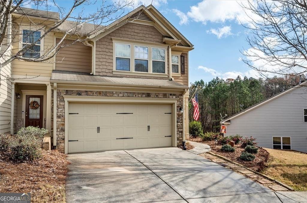 view of front of property with stone siding, an attached garage, and concrete driveway