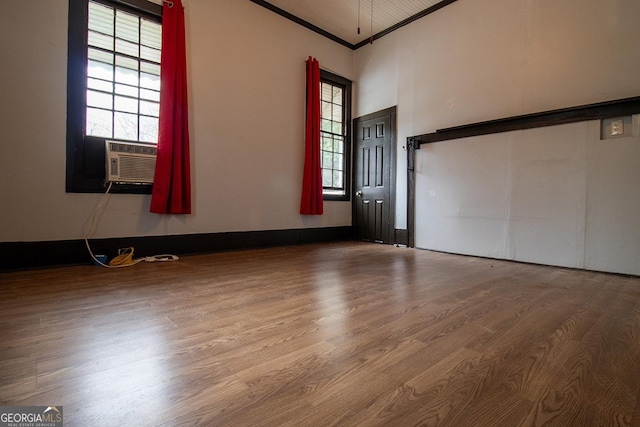 empty room with wood-type flooring, ornamental molding, and cooling unit