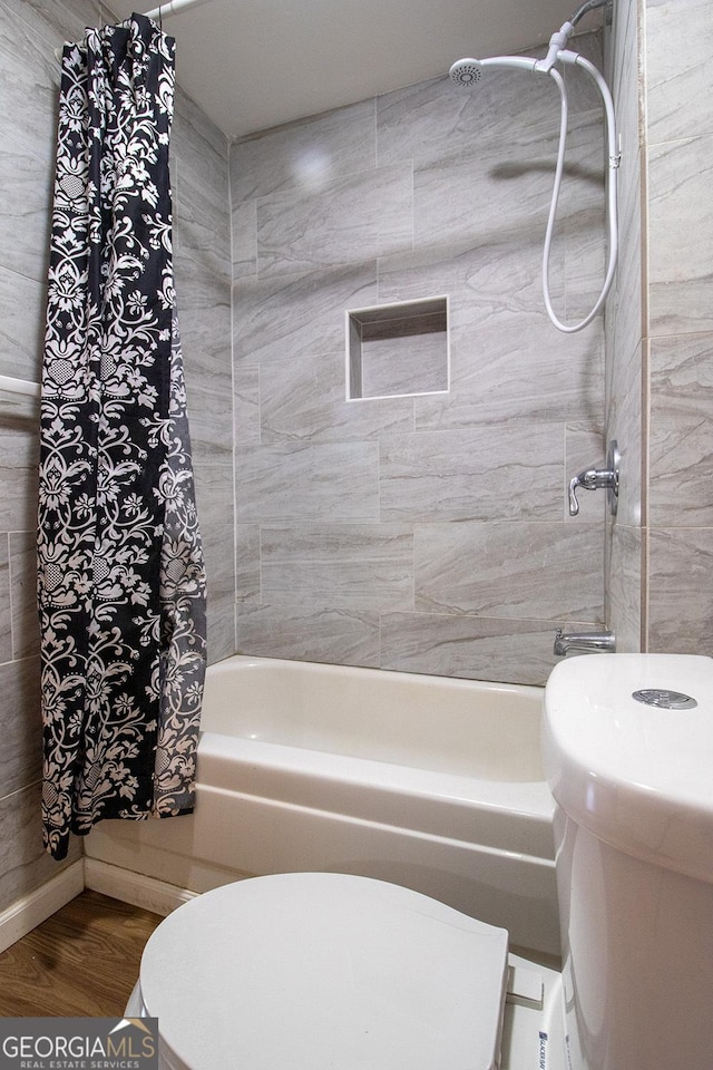 bathroom with shower / bathtub combination with curtain, hardwood / wood-style flooring, and toilet