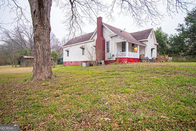 view of property exterior featuring cooling unit, a yard, and a porch