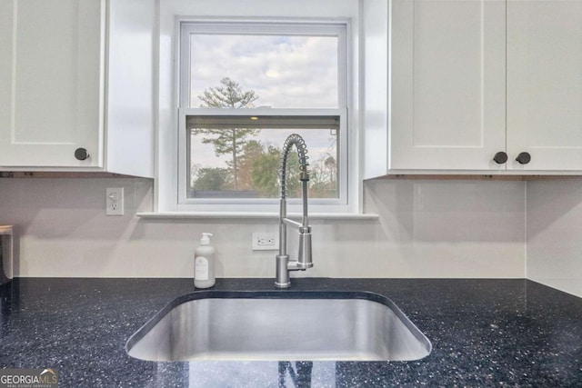 interior details featuring backsplash, sink, and white cabinets