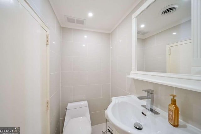 bathroom with sink, tile walls, and toilet