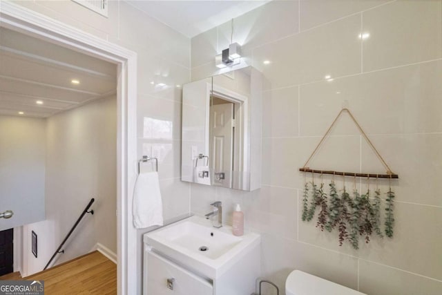 bathroom featuring decorative backsplash, vanity, toilet, and tile walls