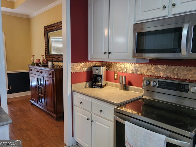 kitchen with hardwood / wood-style flooring, crown molding, appliances with stainless steel finishes, and white cabinets