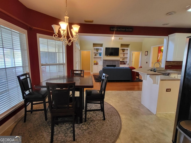 dining room with a tile fireplace, sink, an inviting chandelier, and built in shelves