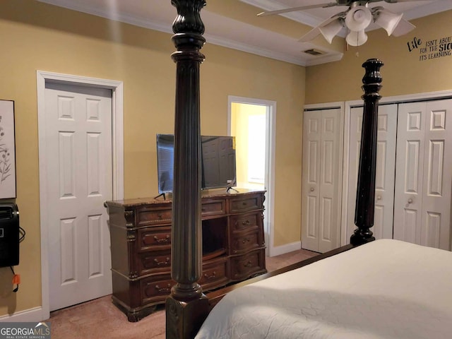 carpeted bedroom with ornamental molding and multiple closets