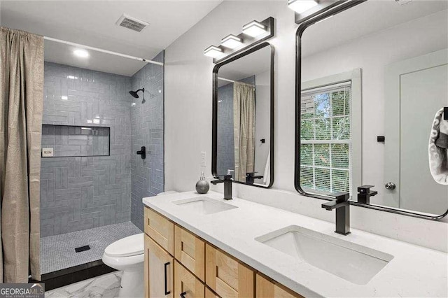 bathroom with tiled shower, vanity, and toilet