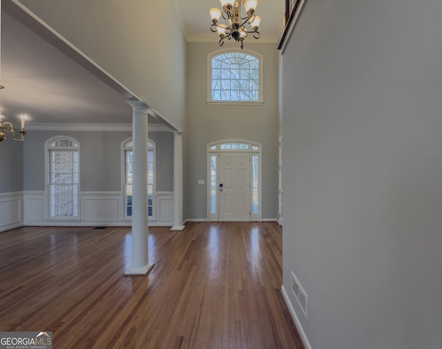 foyer featuring ornate columns, visible vents, a notable chandelier, and wood finished floors