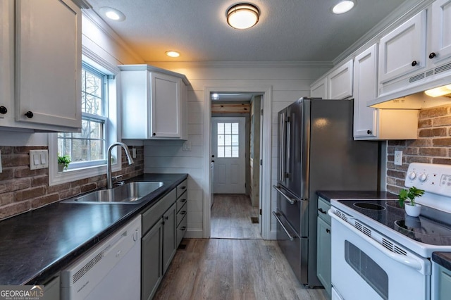 kitchen with white cabinetry, sink, white appliances, and light hardwood / wood-style flooring