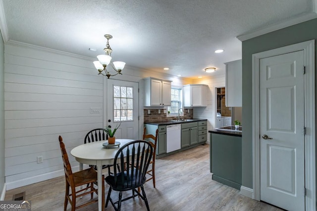 dining area with sink, crown molding, a notable chandelier, light hardwood / wood-style floors, and a textured ceiling