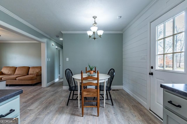 dining room featuring crown molding, a notable chandelier, and light hardwood / wood-style flooring