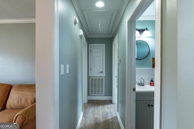 corridor with sink, crown molding, and light hardwood / wood-style floors