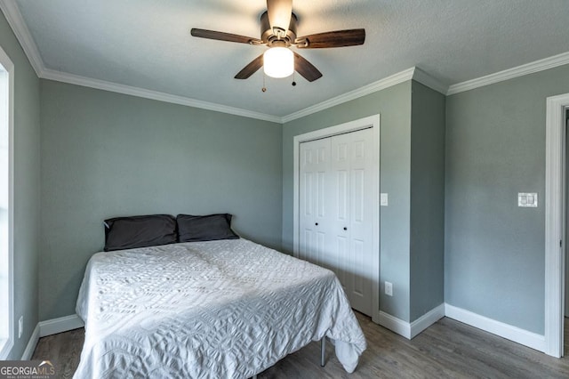 bedroom featuring dark wood-type flooring, ceiling fan, ornamental molding, and a closet