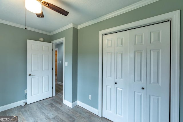 unfurnished bedroom featuring crown molding, ceiling fan, light hardwood / wood-style floors, and a closet