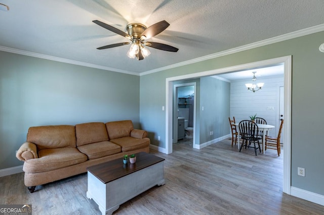 living room with crown molding, wood-type flooring, ceiling fan with notable chandelier, and a textured ceiling