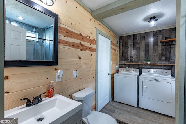 bathroom with wooden walls, washing machine and dryer, vanity, a textured ceiling, and toilet