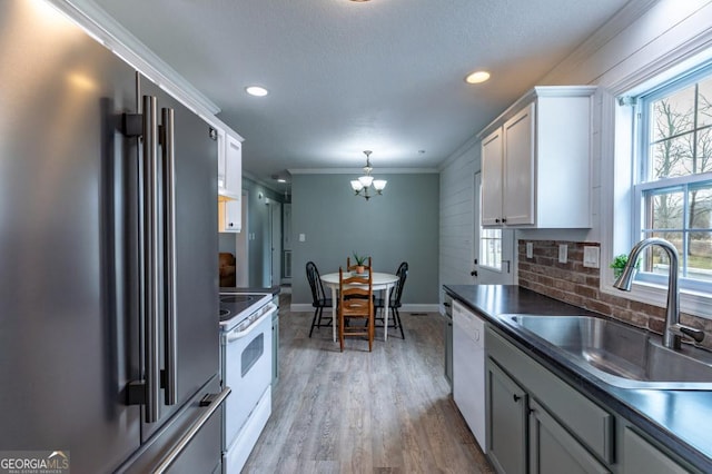 kitchen with white cabinetry, sink, white appliances, and a healthy amount of sunlight