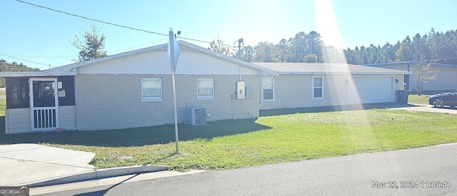 view of side of home with a garage, central AC, and a lawn