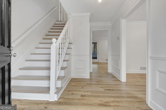 staircase with crown molding and hardwood / wood-style flooring