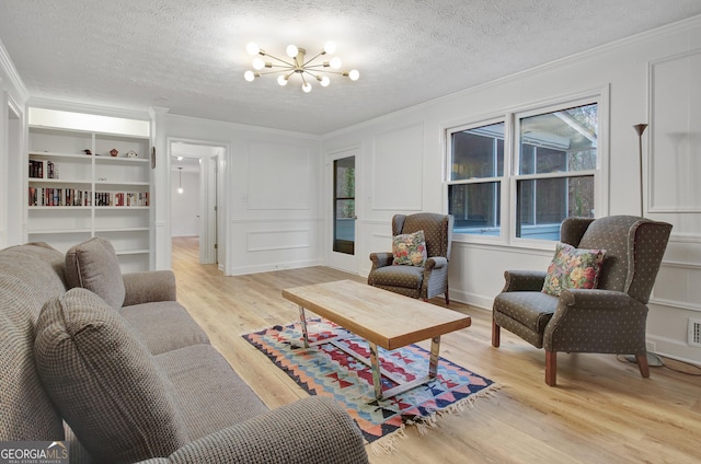 living room featuring light hardwood / wood-style flooring, a notable chandelier, crown molding, a textured ceiling, and built in shelves