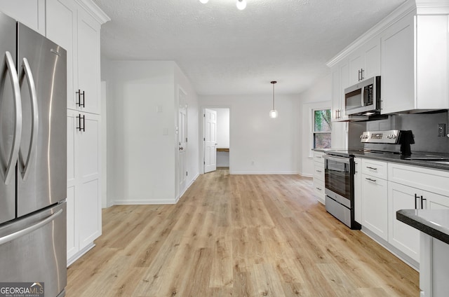 kitchen with white cabinetry, appliances with stainless steel finishes, light wood-type flooring, and decorative light fixtures