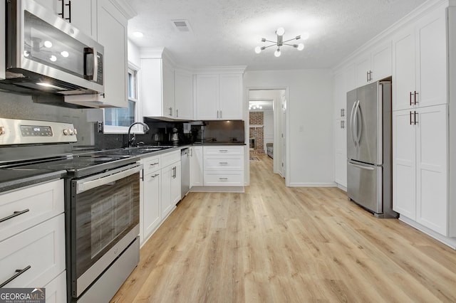 kitchen featuring stainless steel appliances, sink, a textured ceiling, and white cabinets